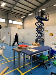 Photo of a warehouse space, clinical beds and workmen