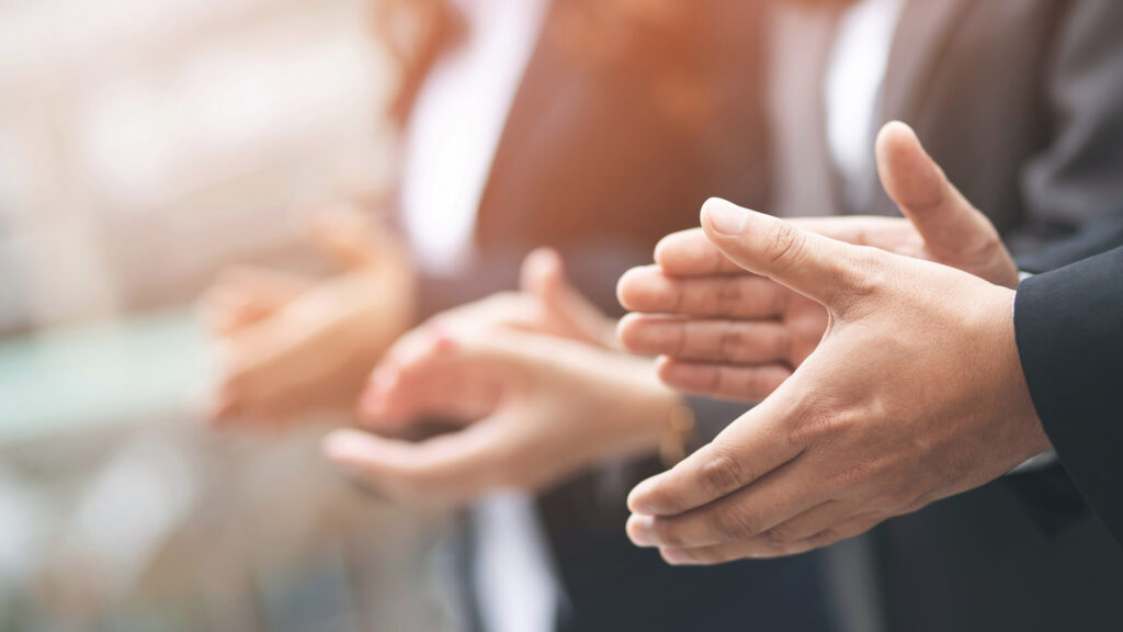 Photo of three pairs of hands clapping