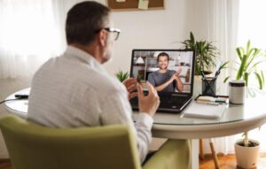 man sign talking virtually on laptop