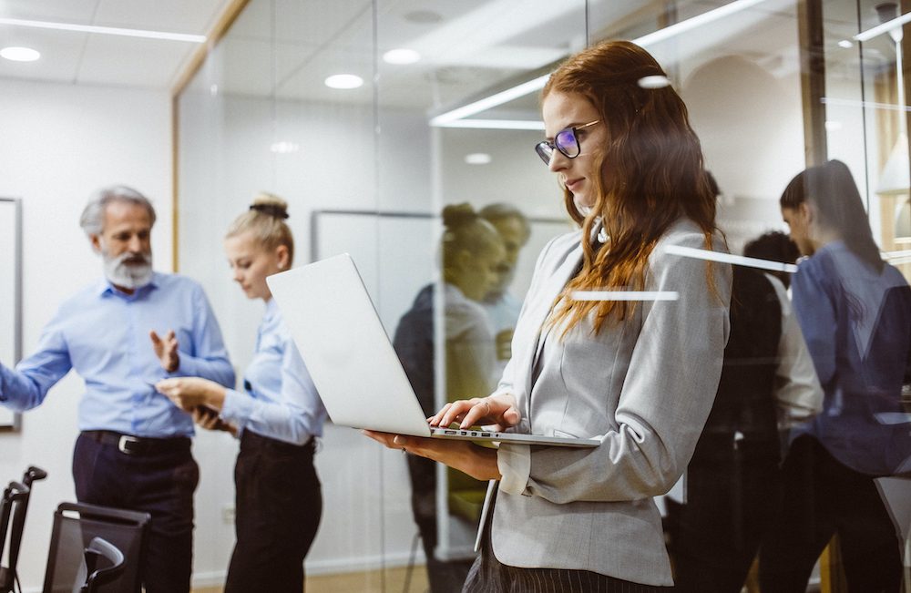 Businesswoman working in the office with colleagues behind